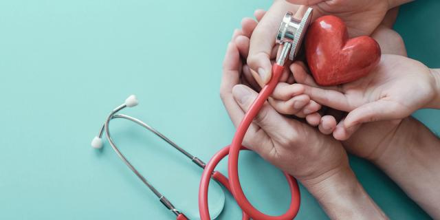 Family hands holding red heart with stethoscope, heart health,  health insurance concept, World heart day, world health day