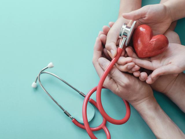 Family hands holding red heart with stethoscope, heart health,  health insurance concept, World heart day, world health day