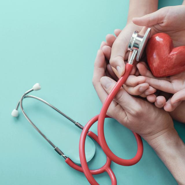 Family hands holding red heart with stethoscope, heart health,  health insurance concept, World heart day, world health day